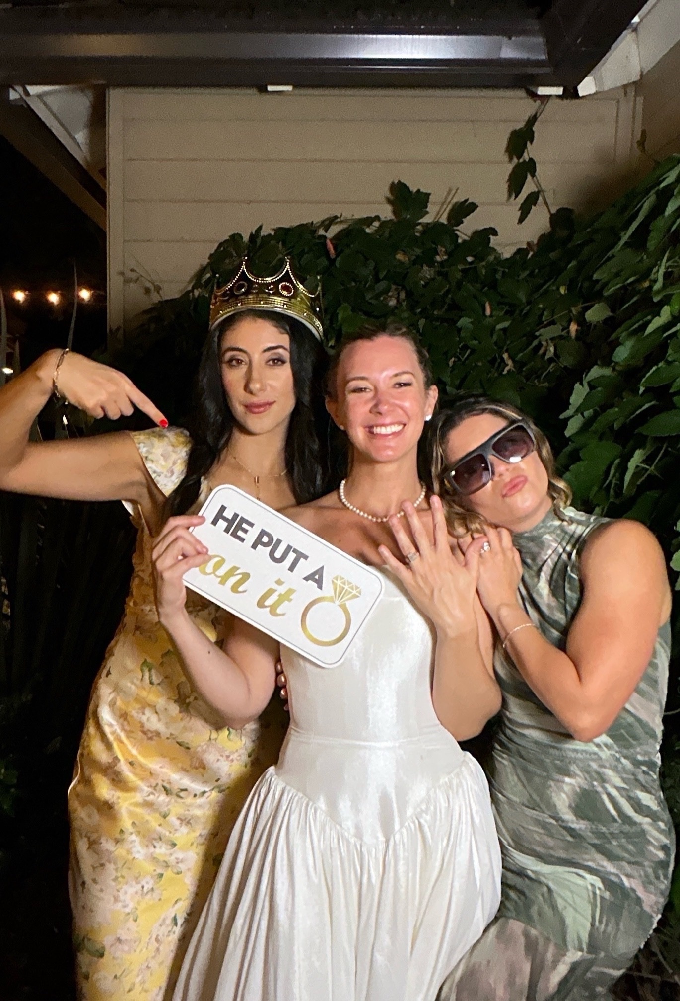 Bride and friends celebrating with a personalized wedding photo booth prop